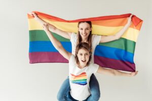 LGBQ Stock Photo Woman Giving Piggyback To Girlfriend With Flag 300x200