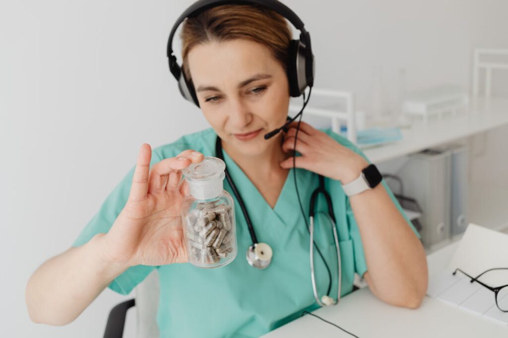 Female doctor with headphones holding a bottle of pills while working in a medical office setting.