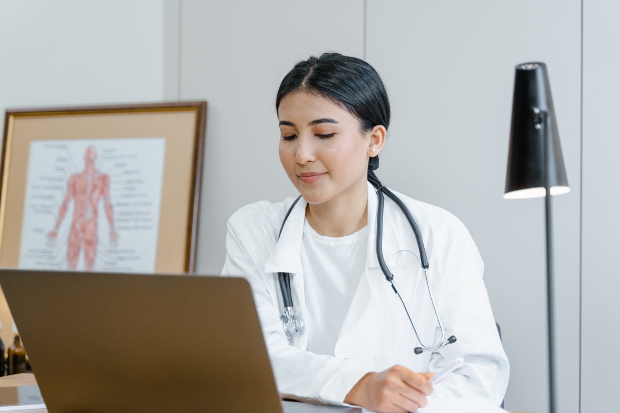 Young female doctor with stethoscope consulting online from office.